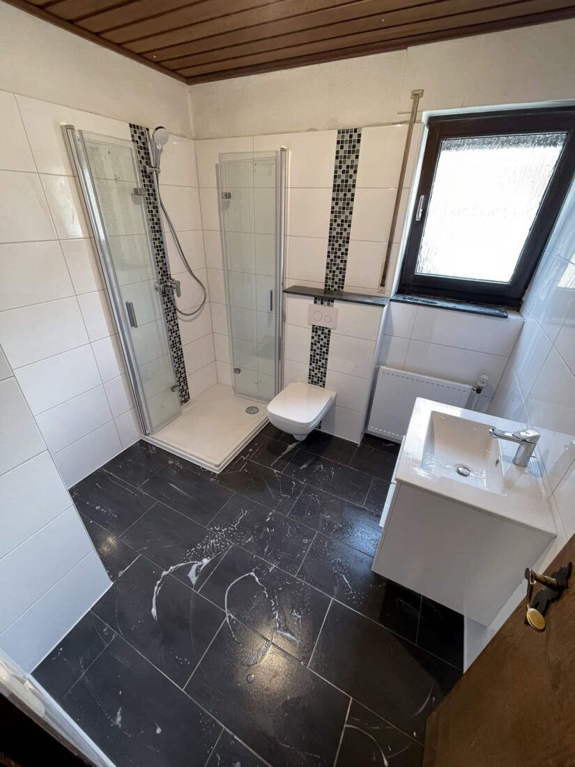 Eckduschkabine mit Klappglastür, Wand-WC und Waschtisch unter Holzdecke – Komplettbad in Essen
